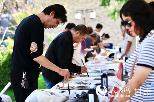 文化体验区内，游客正观摩书画家创作，并参与即兴创作互动。人民网记者 焦隆摄